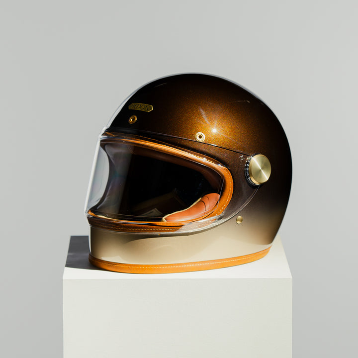 Brown motorcycle helmet on a white stand with a gray background